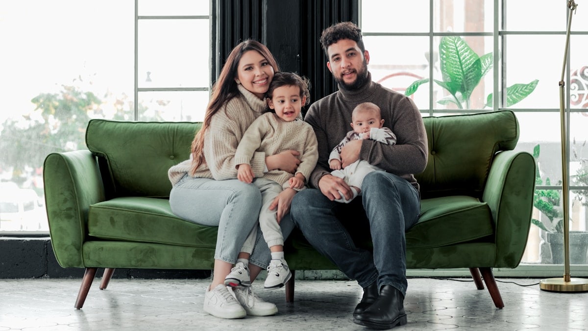 a family sitting on a green couch in a living room